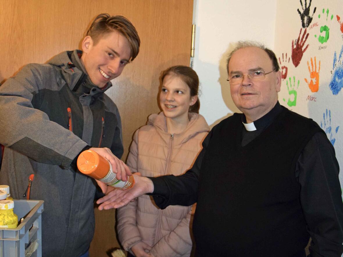 Der künftige Bischof von Augsburg, Prälat Dr. Bertram Meier, lässt sich von Oberministrant Michael Hock die Farbe für einen Handabdruck an der Wand des Ministranten-Treffs auftragen. (Foto: Verspohl-Nitsche / pdke)