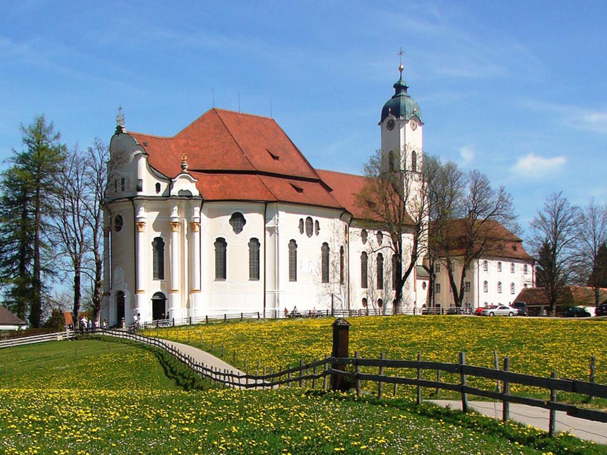 Vor der eindrucksvollen Kulisse der Ammergauer Alpen errichtete Dominikus Zimmermann sein Meisterwerk: die Wallfahrtskirche zum Gegeißelten Heiland auf der Wies, (Foto: Kath. Wallfahrtskuratiestiftung St. Josef - Wies)