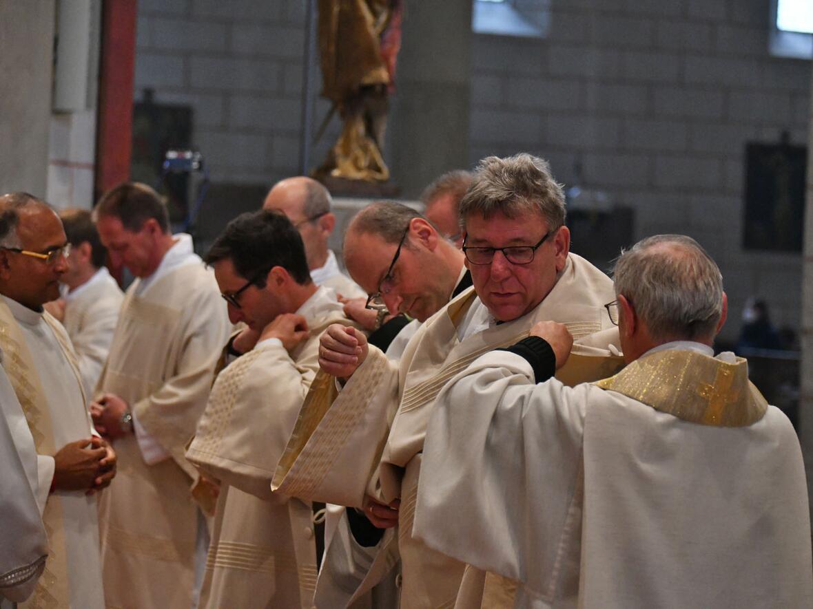 Unterstützt von Mitbrüder im Diakonat legen die neugeweihten Diakone Dalmatik und Stola als ihr Amtsgewand an.