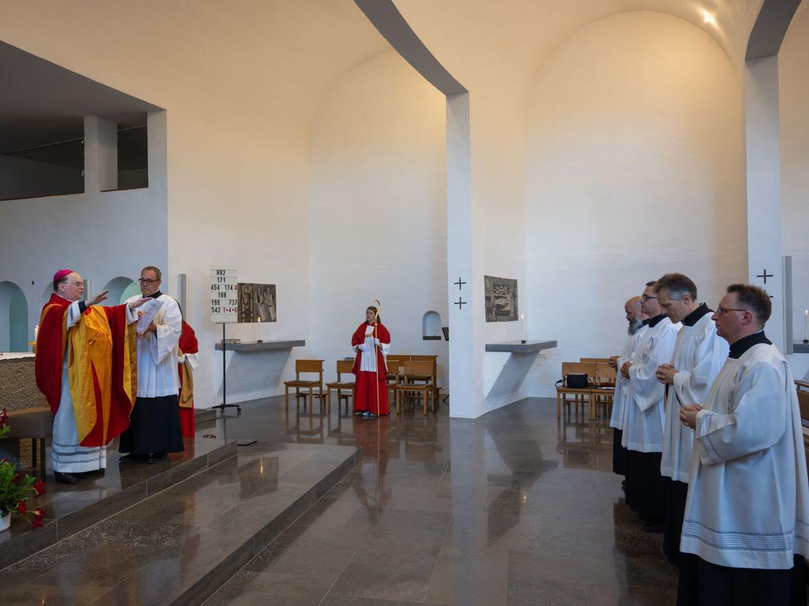 Der Bischof spricht den Segen über die vier Männer.