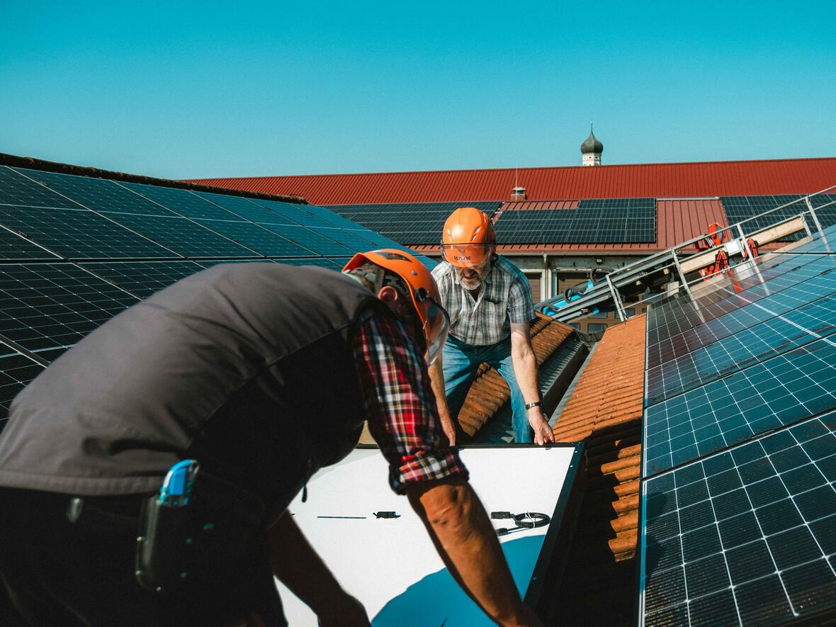 Hoch auf den Dächern von Ursberg: Mitarbeiter des DRW-Baubetriebs montieren ein Photovoltaik-Modul auf dem Dach des Fuhrparks. (Foto: DRW)