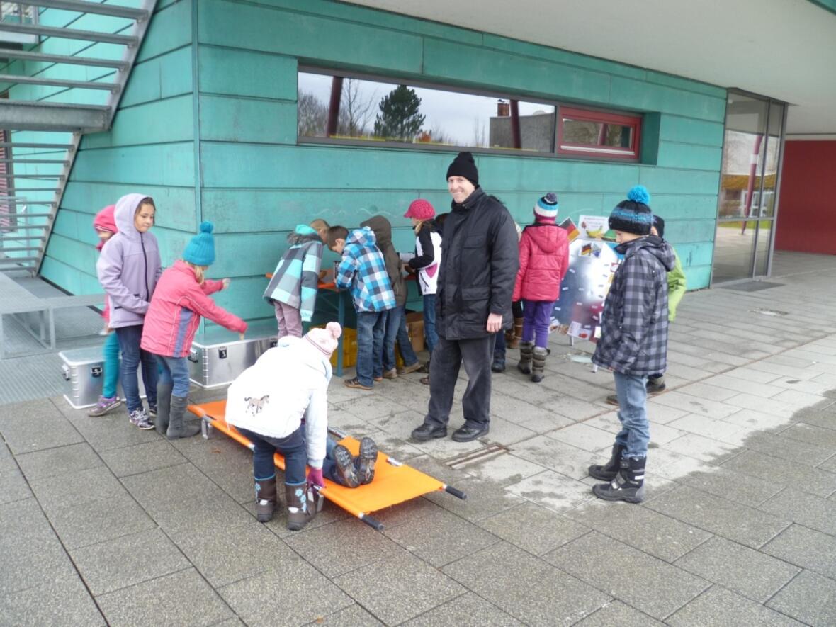 Pfarrer Gugler mit Schülern der 3. Klasse beim Erkunden der Infomaterialien