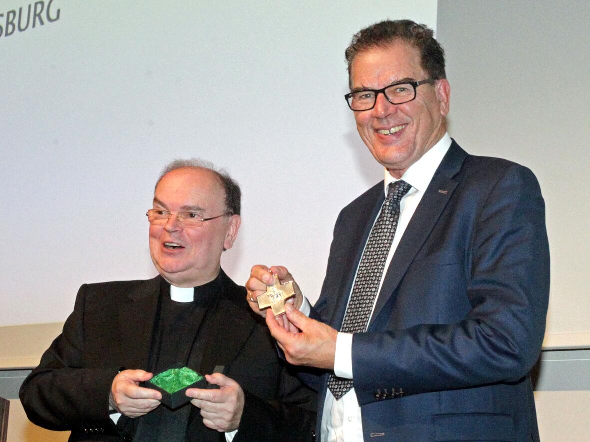 Diözesanadministrator Bertram Meier überreicht Minister Müller das Ulrichskreuz.