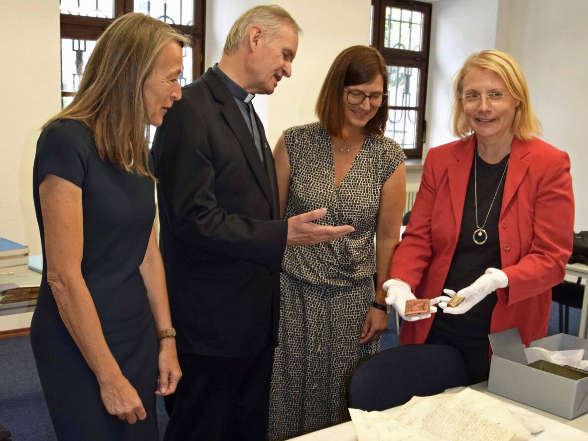 Historikerin und Archäologin Birgit Kata (r.) zeigt der Leiterin des Staatlichen Bauamtes Cornelia Bodenstab (l.) und Stadtpfarrer Monsignore Dr. Bernhard Ehler den von Restauratorin Ursula Dekker-Sturm gesichteten Inhalt der zweiten Zeitkapsel. (Foto: Sabine Verspohl-Nitsche / pdke)