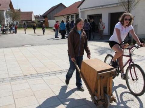 Mädchen beim Rätschen mit großer "Schubkarrenrätsche"