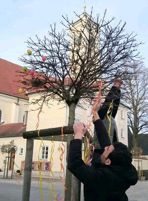 Gemeinschaftsstiftende Aktion vor der Pfarrkirche Mariä Himmelfahrt: Ali und Mohamad, beide Flüchtlinge aus Syrien, helfen in Türkheim beim traditionellen Schmücken der Osterbäume. (Foto: Helferkreis Türkheim/Rummel)