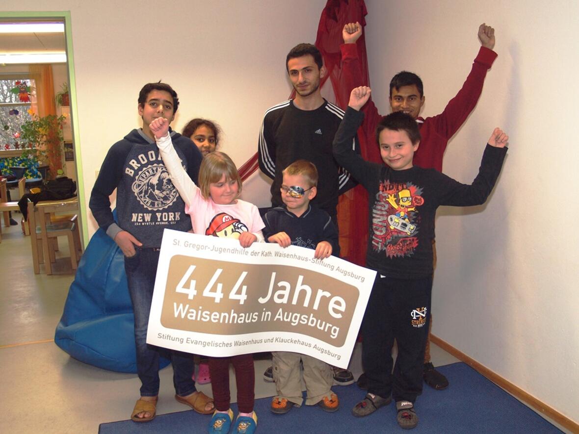 Kinder und Jugendliche präsentieren das Logo, das die St. Gregor Kinder-, Jugend- und Familienhilfe gGmbH der Katholischen Waisenhaus-Stiftung Augsburg und das Evangelische Kinder- und Jugendhilfezentrum der Stiftung Evangelisches Waisenhaus und Klauckehaus Augsburg durch das ungewöhnliche Jubiläumsjahr begleiten wird. (Foto: St. Gregor-Jugendhilfe/Daniela Lutz)