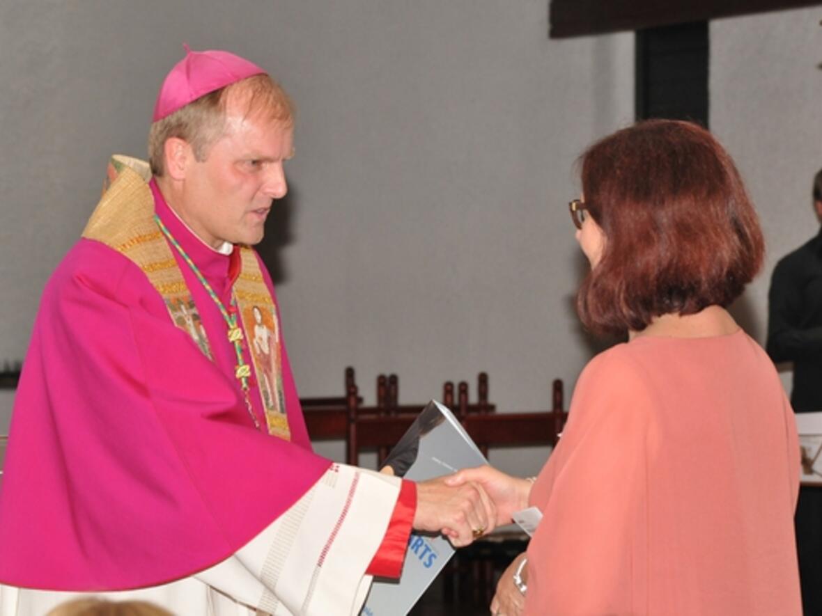 Weihbischof Wörner überreicht einer Berufspraktikantin das Handbuch, das als Begleiter für die religionspädagogische Arbeit sowie die Fort- und Weiterbildung dienen soll. (Foto: Schule und Religionsunterricht)
