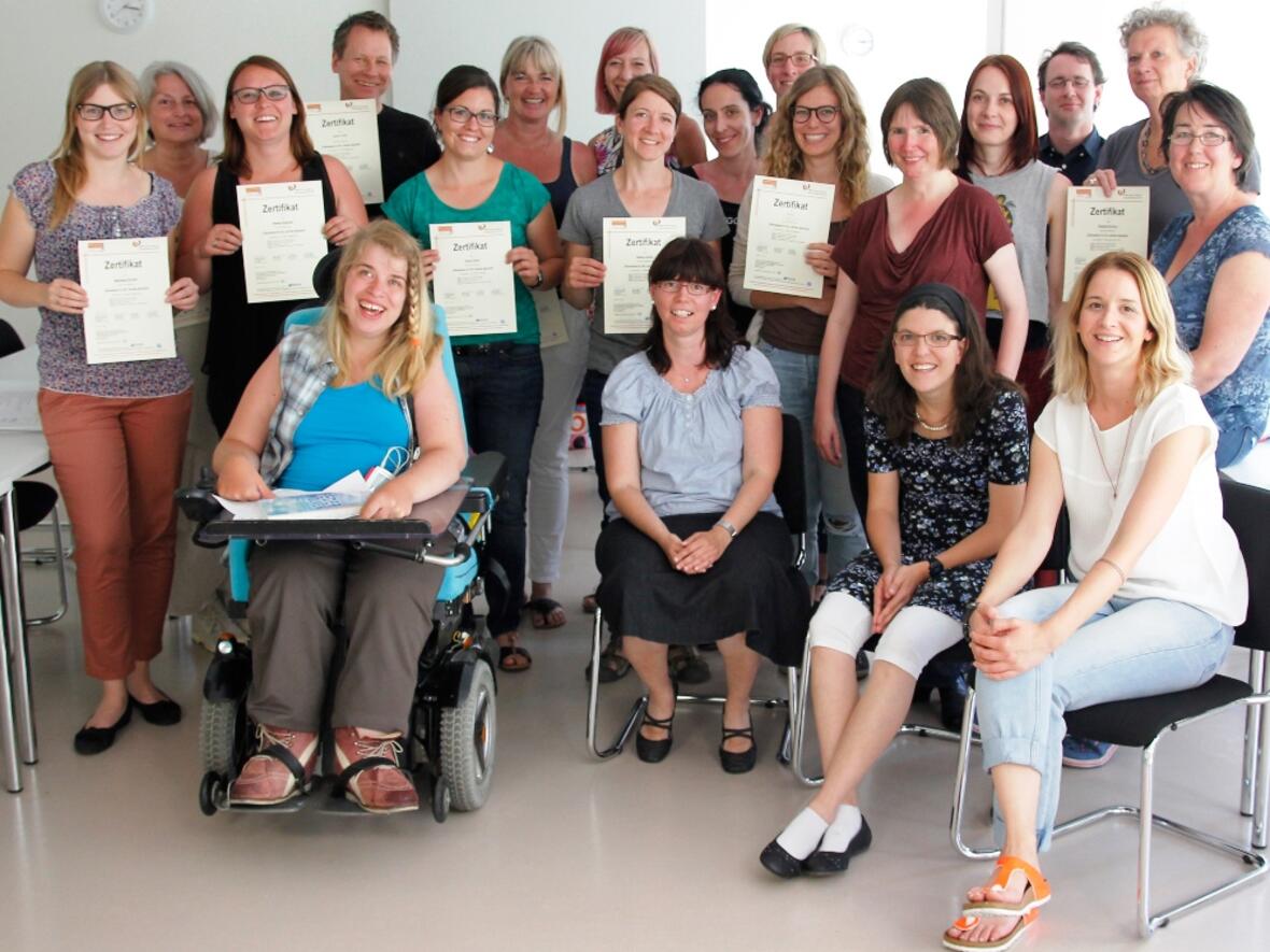 Nach sieben Tagen Ausbildung halten sie ihr Zertifikatszeugnis als Übersetzer/-in für die Leichte Sprache in der Hand. In der ersten Reihe sitzen (von links nach rechts) die drei Prüferinnen Andrea Käb, Maria Hütter und Tanja Greisel, Betroffene, die die übersetzten Texte prüfen, ob sie wirklich verständlich sind und den Kriterien der Leichten Sprache entsprechen. Kristina Wehner (vorne rechts) hat als Dozentin und Übersetzerin für Leichte Sprache sowie Prüferbeauftragte den Kurs geleitet. (Foto: Caritas Augsburg / Bernhard Gattner)