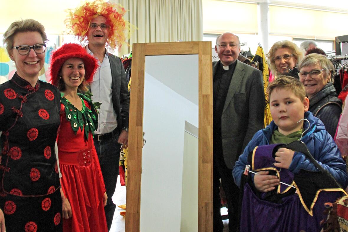 Pfarrer Dr. Ulrich Lindl (rechts neben Spiegel) und Gregor Uhl (links) eröffnen mit dem ehrenamtlichen Team aus Lauingen und Kunden die diesjährigen Secondhand-Faschingsmärkte der aktion hoffnung. (Foto: Karin Stippler / aktion hoffnung)