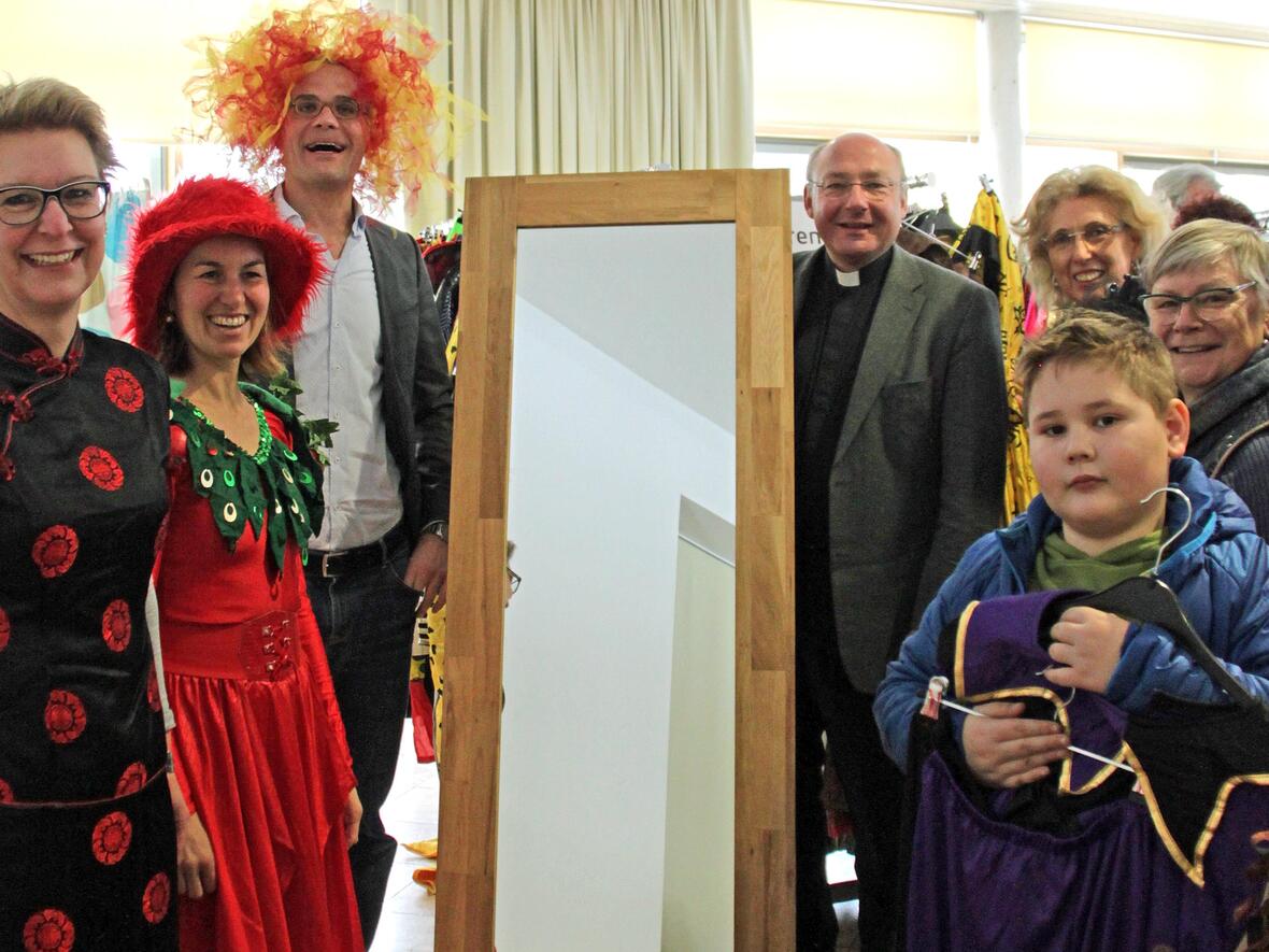 Pfarrer Dr. Ulrich Lindl (rechts neben Spiegel) und Gregor Uhl (links) eröffnen mit dem ehrenamtlichen Team aus Lauingen und Kunden die diesjährigen Secondhand-Faschingsmärkte der aktion hoffnung. (Foto: Karin Stippler / aktion hoffnung)