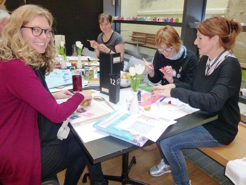 Die Designerin Eva Neumann (recht) und Tanja Blum (links) haben zu „Kunst & Kuchen“ ins Café Samocca geladen. (Foto: Caritas Augsburg/Gerlinde Knoller)
