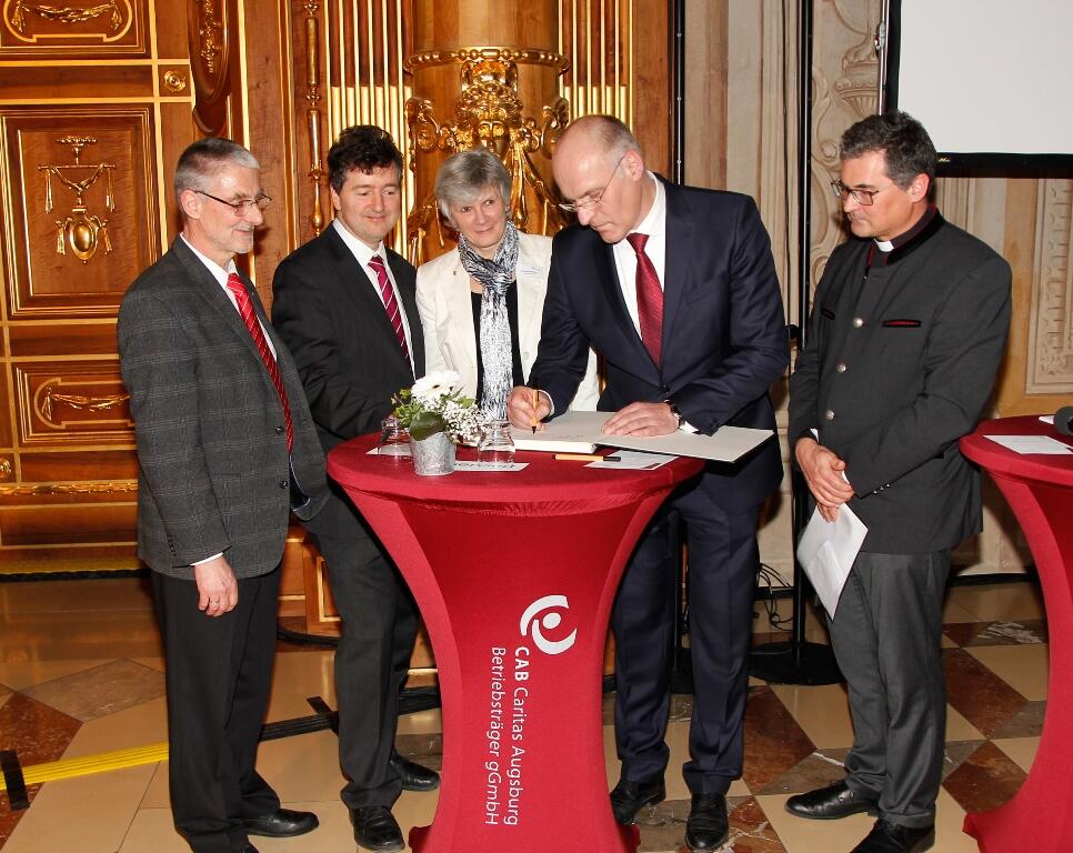 Oberbürgermeister Dr. Kurt Gribl trug als erster seine Dankesworte in das große Erinnungsbuch anlässlich der Bombenevakuierung ein. Foto: Caritas Augsburg/Bernhard Gattner. 