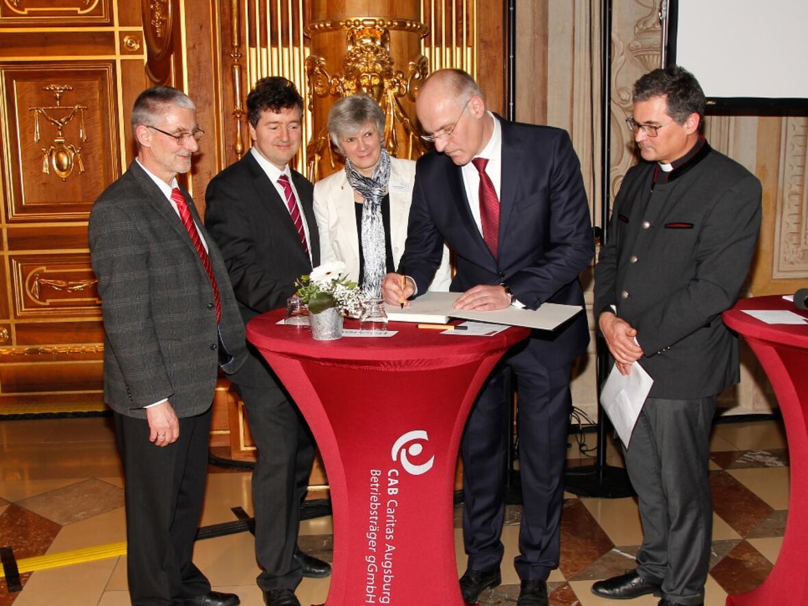 Oberbürgermeister Dr. Kurt Gribl trug als erster seine Dankesworte in das große Erinnungsbuch anlässlich der Bombenevakuierung ein. Foto: Caritas Augsburg/Bernhard Gattner. 