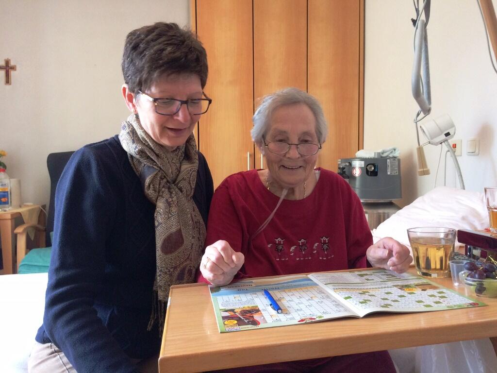 Die Pflegedienstleiterin Daniela Renzmann sitzt neben Lisa Lebold, die ein Kreuzworträtsel löst. (Foto: Dagmar Weindl)