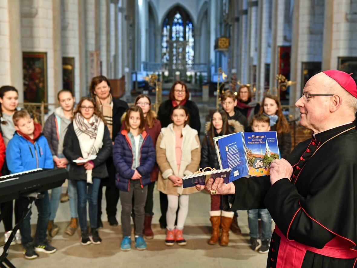 Bischof Konrad erklärt bei der Übergabe des neuen Domführers für Kinder, wie er diesen benutzen würde. (Foto: Nicolas Schnall / pba)