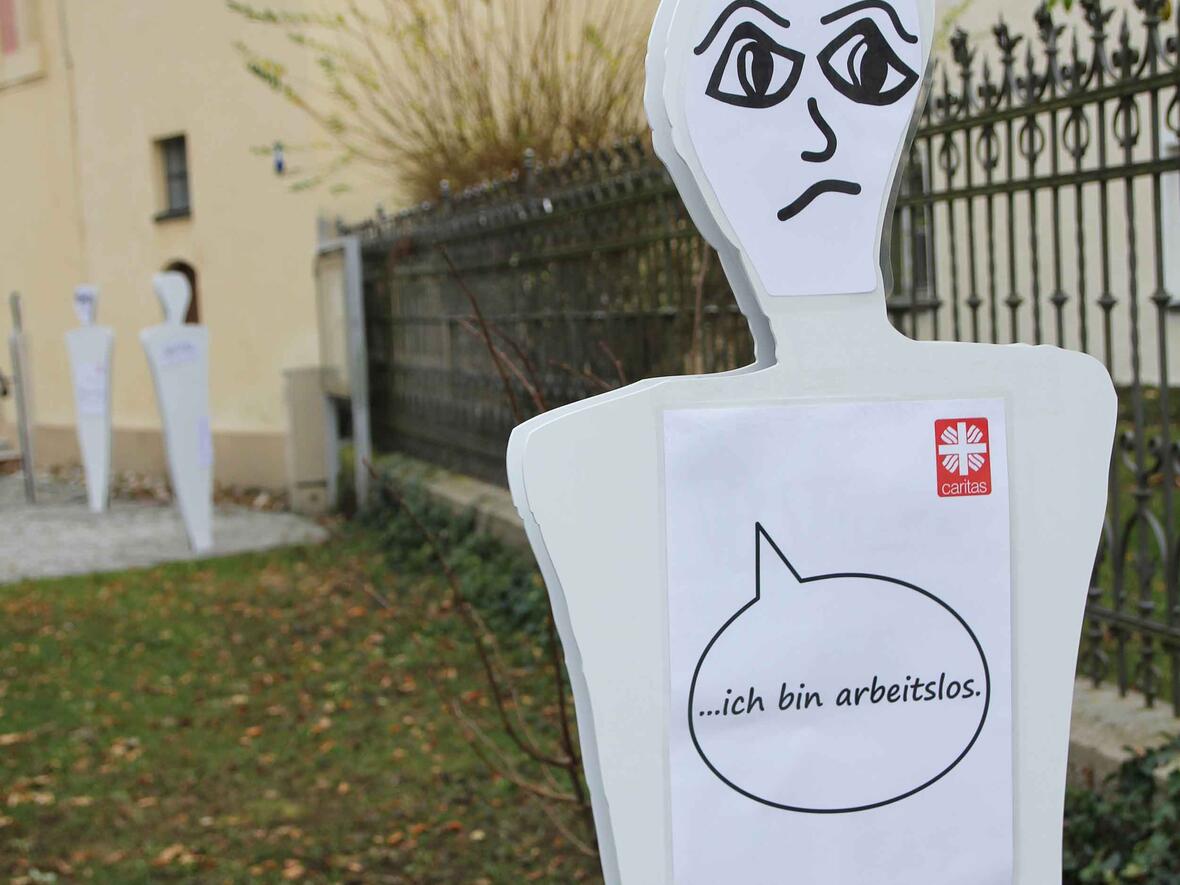 Lebensgroße Figuren auf dem Vorplatz der Heilig Geist Kirche in Neuburg machen auf Armutssituationen aufmerksam (Foto: Bernhard Gattner / Caritas).