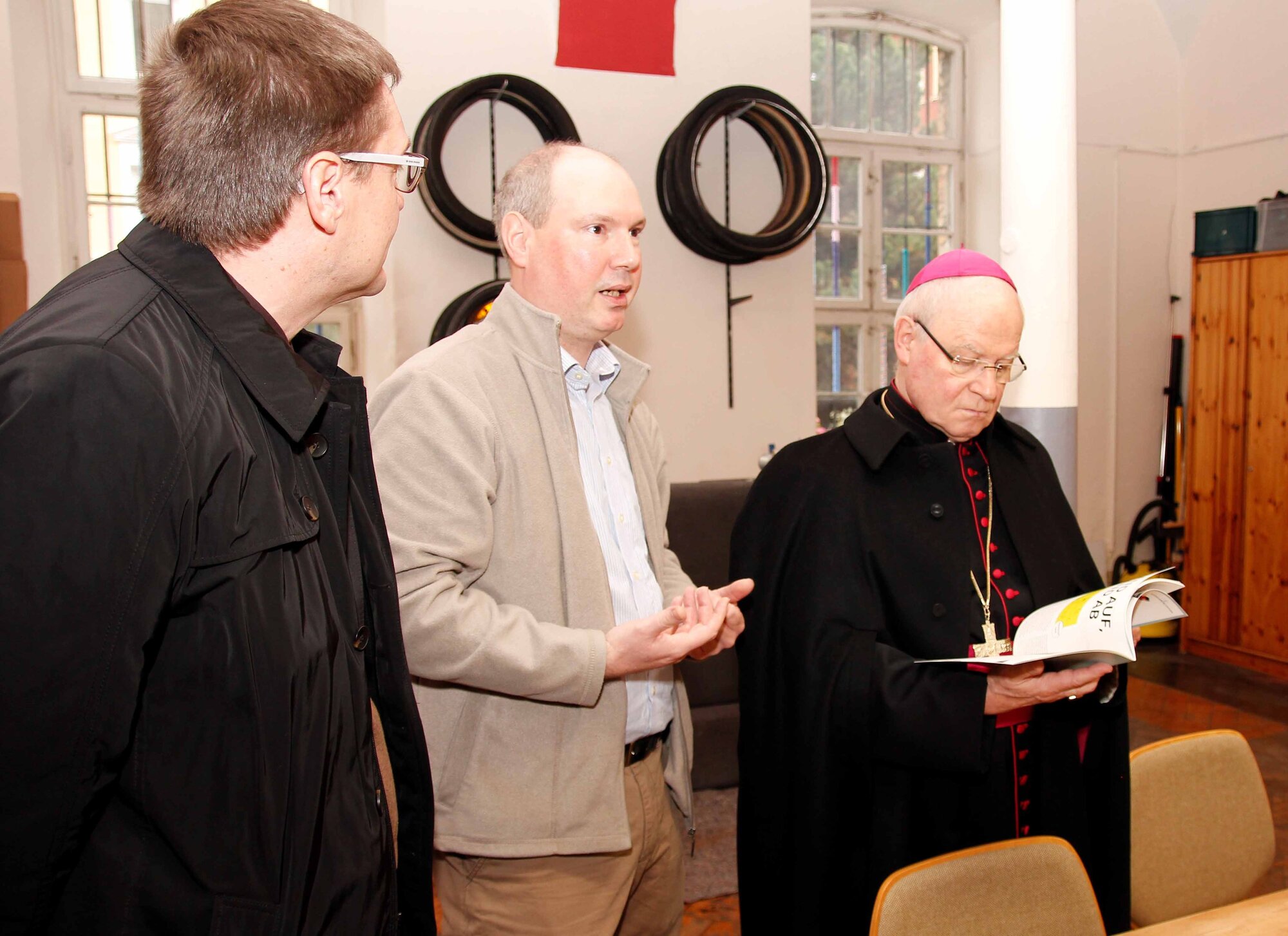 Holger Thoma, Leiter des Projektes "Voll dabei" (Mitte), erläutert Bischof Dr. Konrad Zdarsa und dem diözesanen Flüchtlingsbeauftragten, Diakon Ralf Eger, das Projekt, unter anderem was alles in der Fahrradwerkstatt geleistet wird. (Foto: Caritas/Bernhard Gattner)