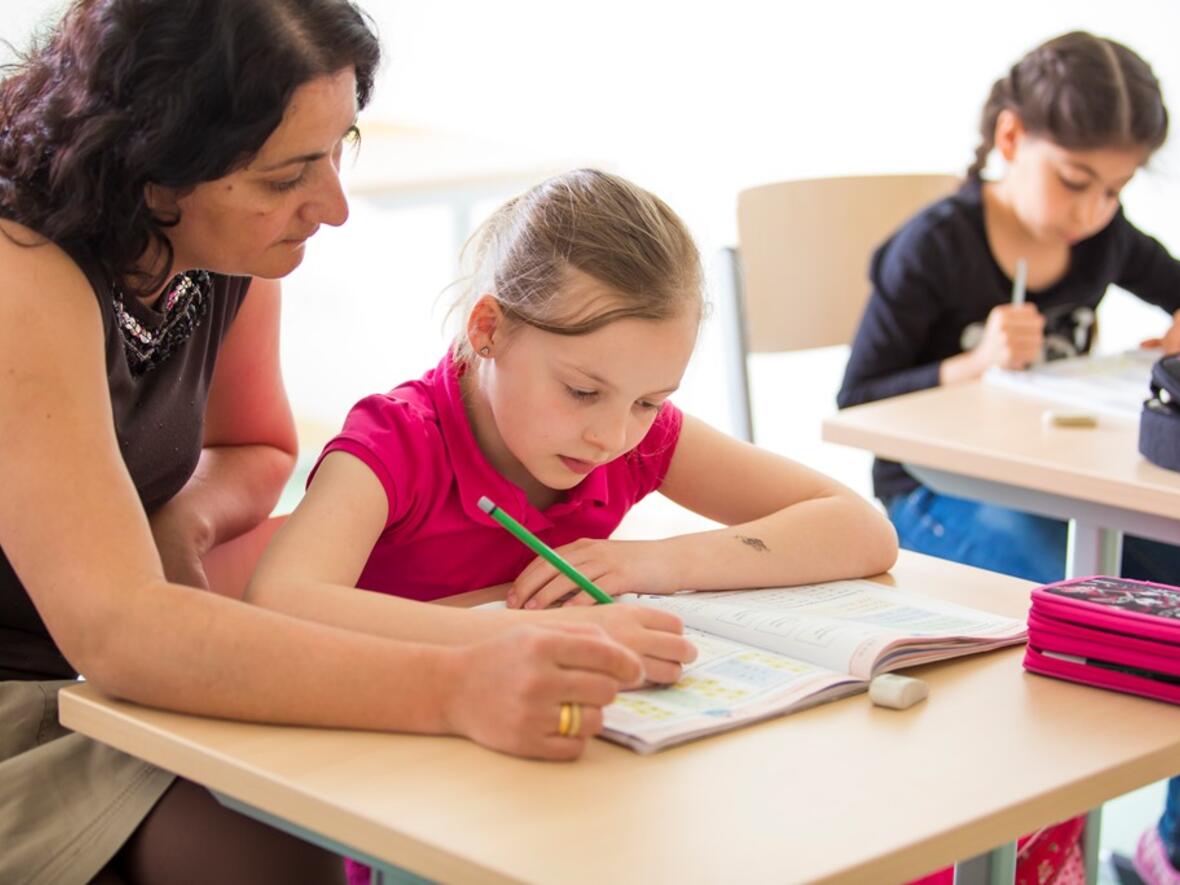 Mitarbeiterinnen des Familienzentrums unterstützen Kinder bei den Hausaufgaben. (Foto: KJF)