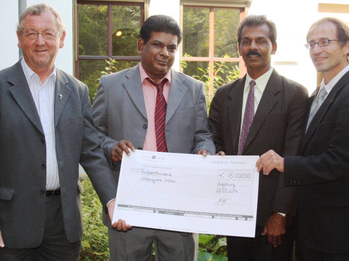 Freude bei den Gästen aus Indien über den Spendenscheck, den der Augsburger Kolping-Diözesanpräses Alois Zeller (links) und Werner Moritz, Geschäftsführer der Kolpingstiftung-Rudolf-Geiselberger (rechts), überreichten. (Foto: Kolping)