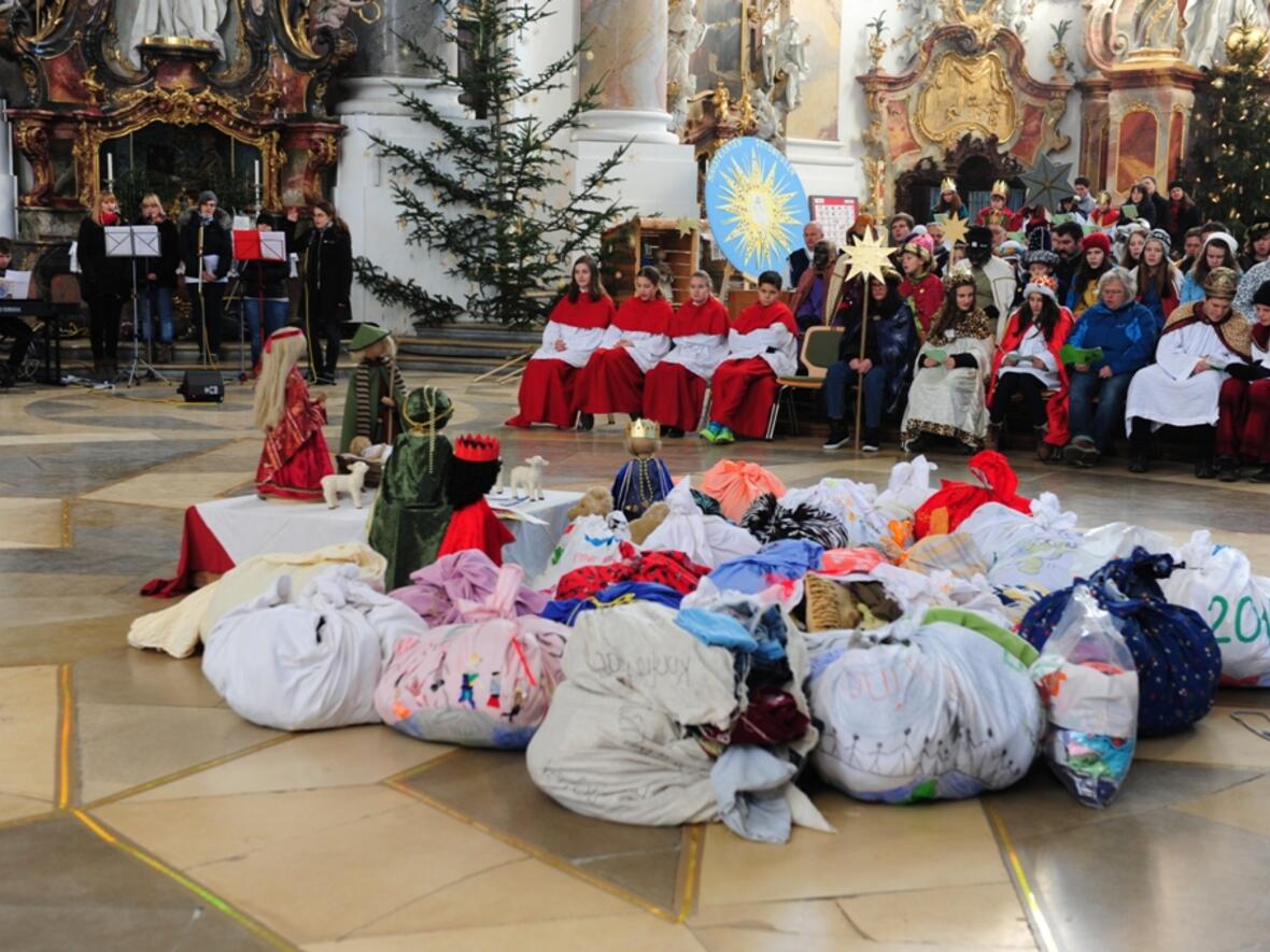 Während des Wortgottesdienstes legten die Sternsingergruppen ihre mitgebrachten Päckchen mit Kleidern an der Krippe ab. Die Pakete erinnerten an Flüchtlingspakete.  