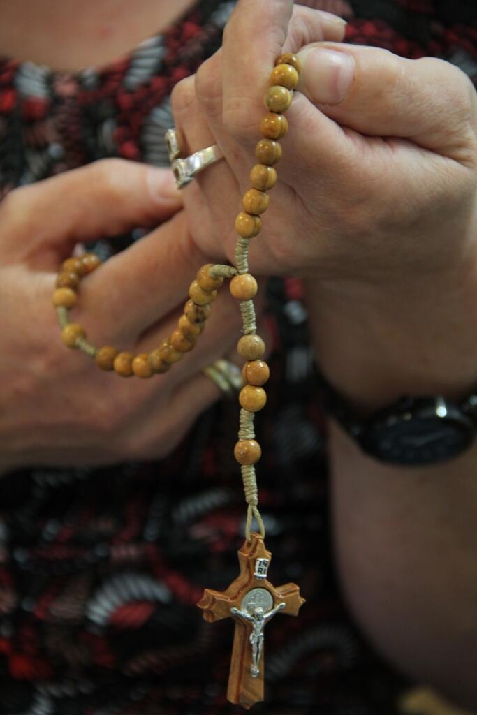 Eine Frau betet den Rosenkranz.