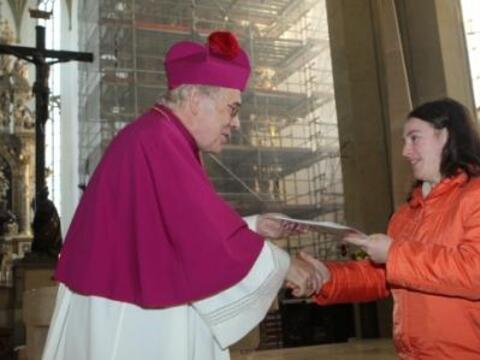 Weihbischof Josef Grünwald überreicht Ursula Bertele das Abschlusszeugnis des bestandenen C-Kurses.