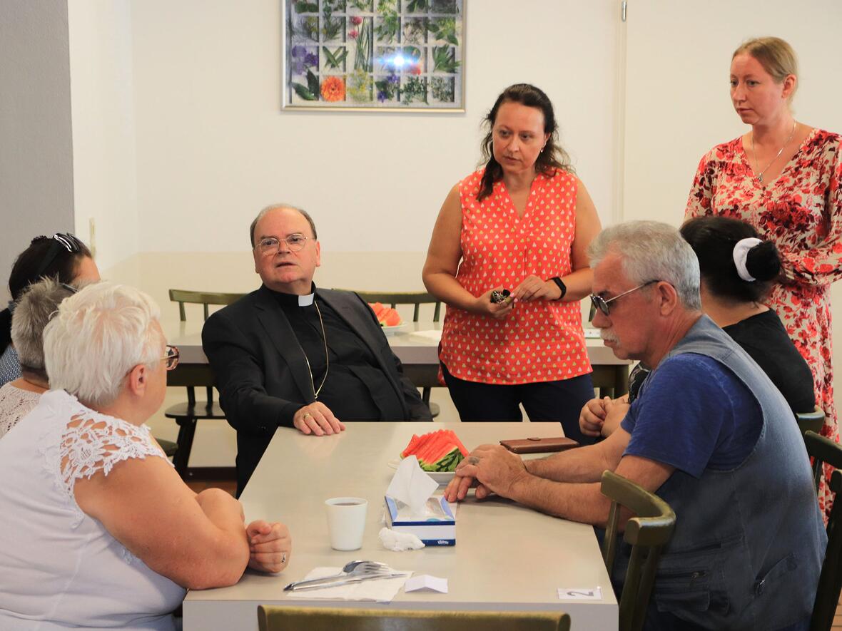 Bischof Bertram nahm sich für das Gespräch mit ukrainischen Flüchtlingen sehr viel Zeit. Die Migrationsberaterin der Caritas Lilli Martel (li.stehend) und Antonova Alla, selbst Flüchtling, halfen bei der Übersetzung. (Foto: Caritas Augsburg / Bernhard Gattner)