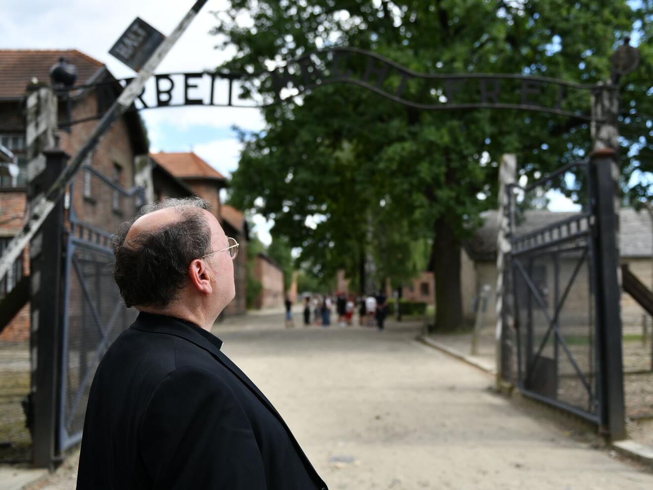 Bischof Bertram vor dem Eingangsbereich des Stammlagers Auschwitz mit dem berüchtigten Spruchband "Arbeit macht frei" (Fotos: Julian Schmidt / pba)