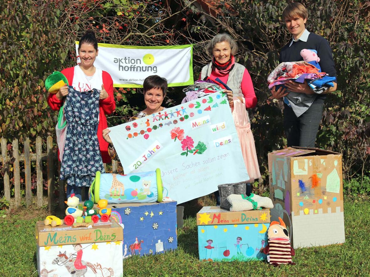 (von rechts nach links) Geschäftsführer Johannes Müller und die Mitarbeiterinnen Maria Fischer, Andrea Haslacher und Lisa Glas freuen sich über die ersten Kleiderspenden für die Aktion „Meins wird Deins“, die in schön gestalteten Kartons im Sortierzentrum der aktion hoffnung in Ettringen eingetroffen sind. (Foto: Franziska Reißner / aktion hoffnung)