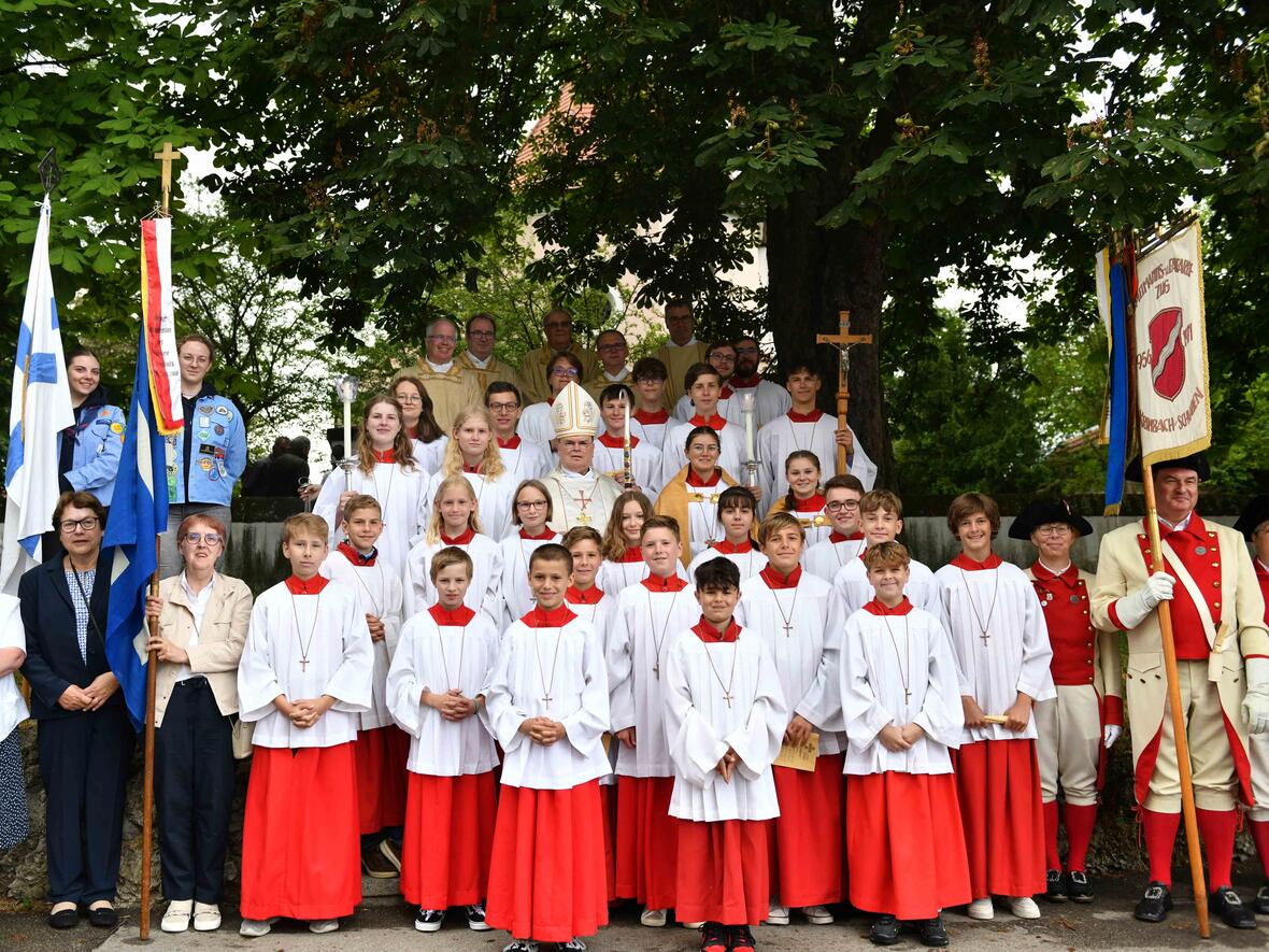 Ein Gruppenfoto mit den Fahnenabordnungen der unterschiedlichen Vereine, den Ministrantinnen und Ministranten sowie den Zelebranten am Eingang zur Ulrichskirche. 
