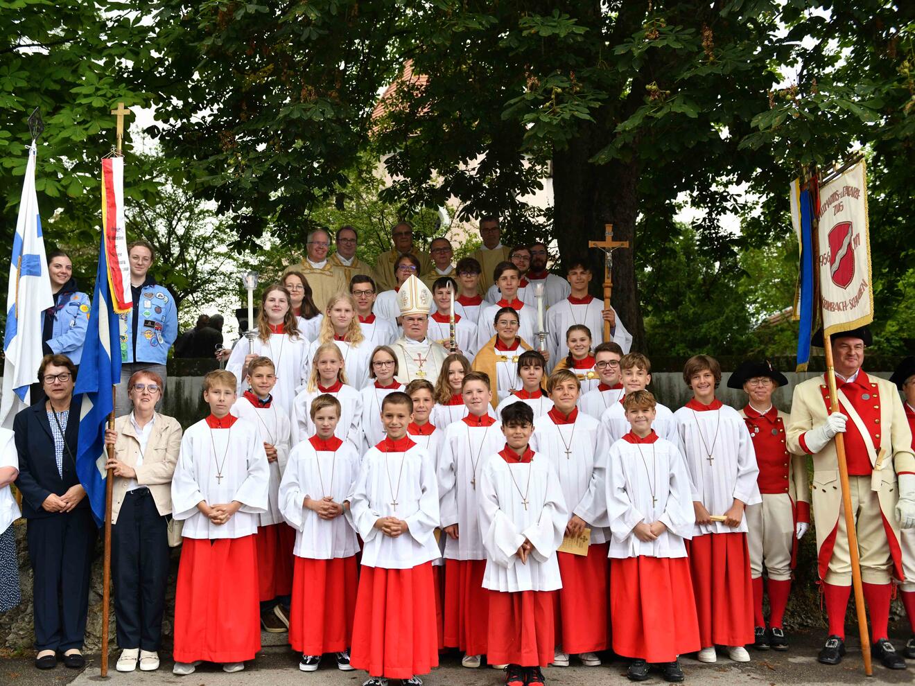 Ein Gruppenfoto mit den Fahnenabordnungen der unterschiedlichen Vereine, den Ministrantinnen und Ministranten sowie den Zelebranten am Eingang zur Ulrichskirche. 