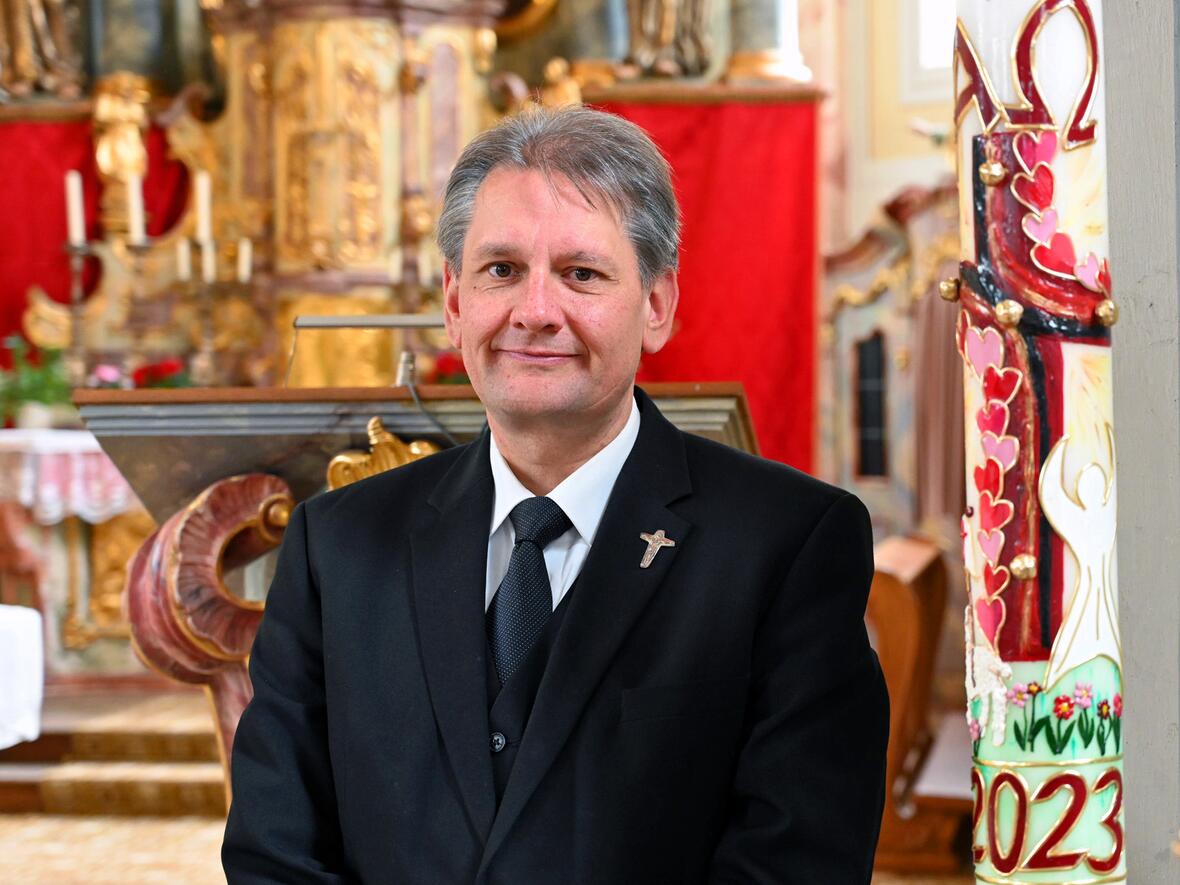 Dekan Ralf Czech an seinem Lieblingsort in der Pfarrkirche von Erkheim, dem Taufbecken mit der Osterkerze. (Foto: Leander Stork / pba)
