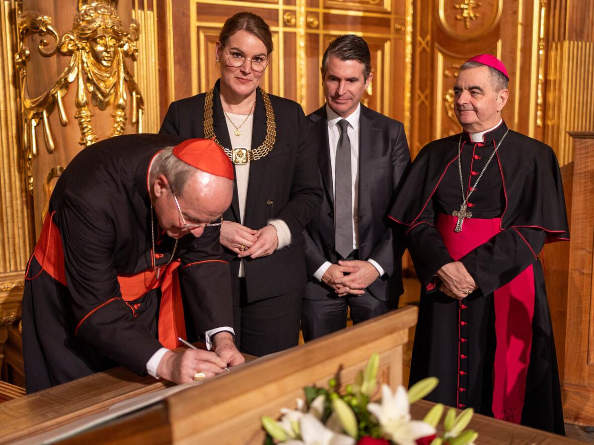 Kardinal Christoph Schönborn trägt sich ins Goldene Buch der Stadt Augsburg ein. (Foto: Julian Schmidt /pba)
