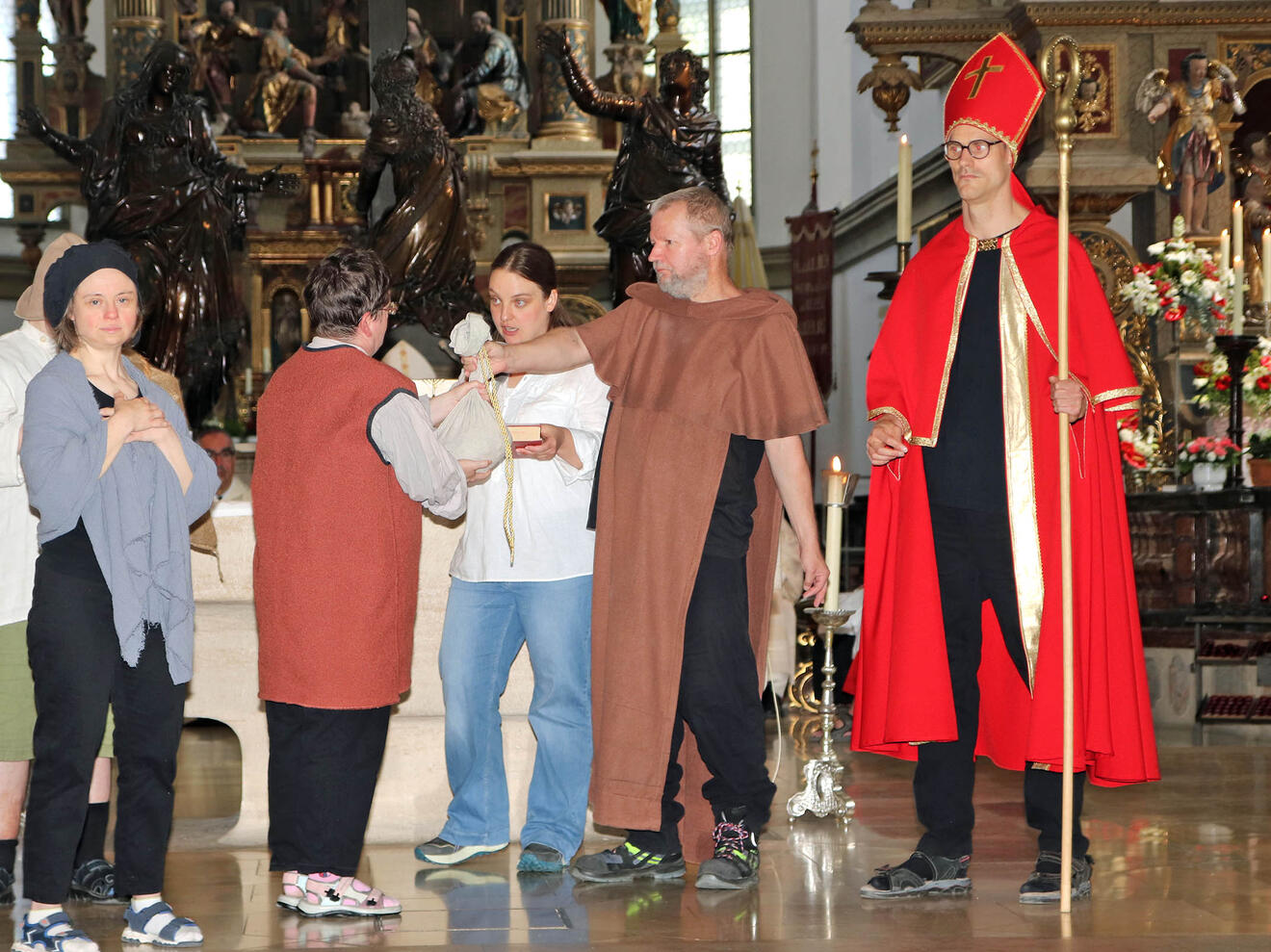 Die Theatergruppe der CAB-Caritas aus Mering führte vor dem Altar in der Ulrichsbasilika ein kleines Theaterstück auf und erzählte davon, dass der Augsburger Bistumspatron trotz aller Zerstörung, des Hungers und Leides den Menschen Mut machte, indem er ihnen in ihrer Not half. (Foto: Caritas Augsburg / Bernhard Gattner)