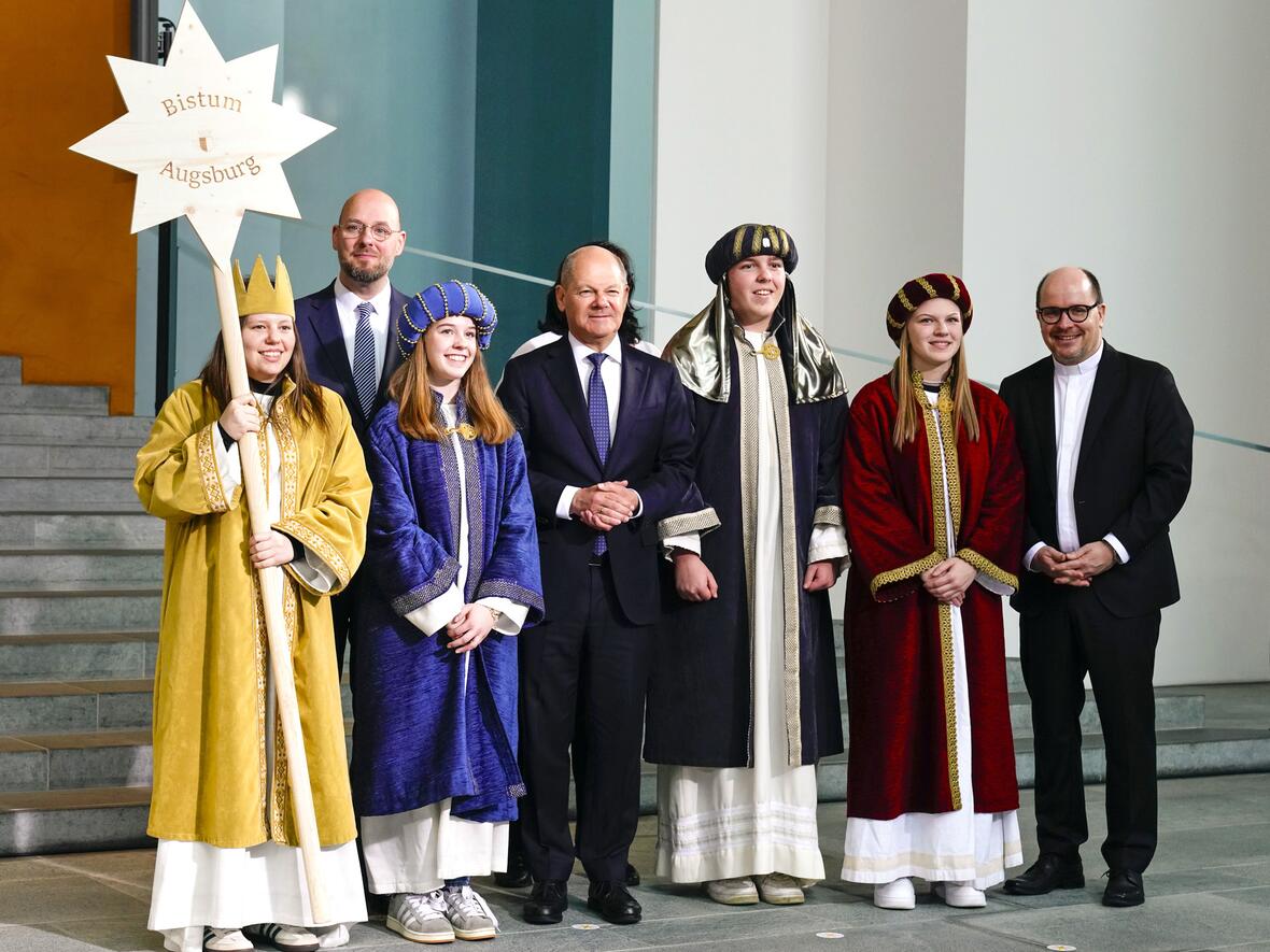 Die Sternsinger Florian (16), Gisela (16), Riana (16) und Antonia (16) sowie Begleiterin Christine Dietrich (auf dem Foto verdeckt) aus der Pfarrgemeinde St. Martin in Aresing vertraten das Bistum Augsburg am Dienstagmorgen beim Sternsingerempfang von Bundeskanzler Olaf Scholz zur 67. Aktion Dreikönigssingen. Zum Gruppenfoto mit dem Kanzler stellten sie sich gemeinsam mit Pfarrer Dirk Bingener, Präsident des Kindermissionswerks ‚Die Sternsinger‘, und Domvikar Stefan Ottersbach, Bundespräses des Bundes der Deutschen Katholischen Jugend (BDKJ), im Bundeskanzleramt auf. (Foto: Friedrich Stark / Kindermissionswerk)
