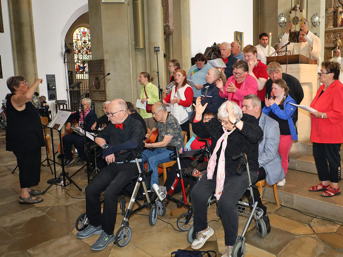 Sie gehören zu den Schätzen der Kirche: Der Johannes-Chor der Stiftung Sankt Johannes in Marxheim, der den Wallfahrtsgottesdienst mit seiner Musik zu einem schönen Erlebnis machte. Im Hintergrund steht Diözesan-Caritasdirektor Diakon Markus Müller mit dem Evangeliar in der Hand. (Foto: Caritas Augsburg / Bernhard Gattner)